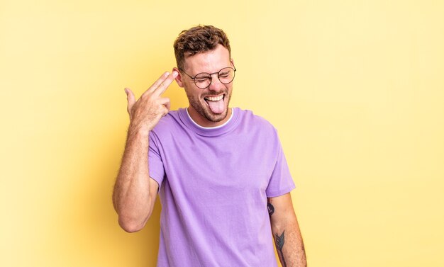 Young handsome hispanic man looking unhappy and stressed, suicide gesture making gun sign with hand, pointing to head