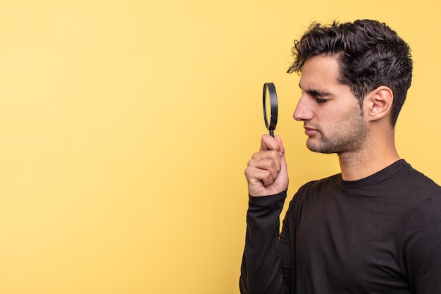 Young handsome hispanic man magnifying glass concept