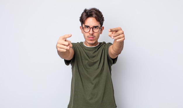 Young handsome hispanic man pointing forward at camera with both fingers and angry expression, telling you to do your duty