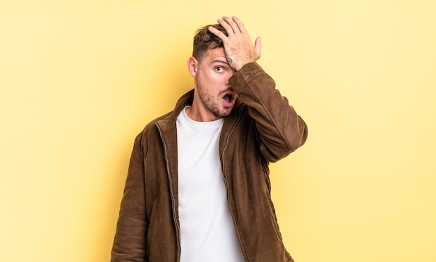 Young handsome hispanic man raising palm to forehead thinking oops, after making a stupid mistake or remembering, feeling dumb