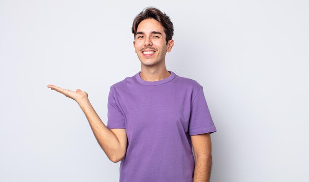 Young handsome hispanic man smiling, feeling confident, successful and happy, showing concept or idea on copy space on the side