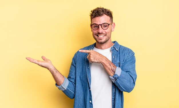 Young handsome hispanic man smiling, feeling happy, carefree and satisfied, pointing to concept or idea on copy space on the side