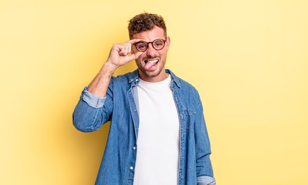 Young handsome hispanic man smiling happily with funny face, joking and looking through peephole, spying on secrets