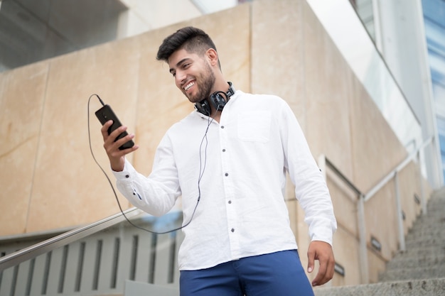 Giovane uomo ispanico bello che utilizza smartphone all'aperto