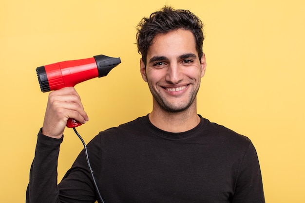 Young handsome hispanic man with a hair dryer