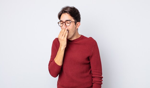 Young handsome hispanic man yawning lazily early in the morning, waking and looking sleepy, tired and bored