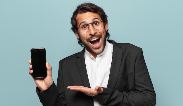 Young handsome indian businesman showing his telephone empty screen