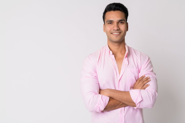 Молодой красивый индийский бизнесмен в розовой рубашке у белой стены