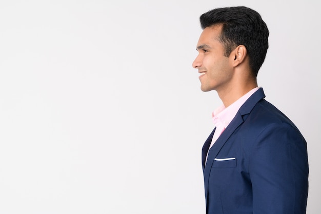 young handsome Indian businessman wearing suit against white wall