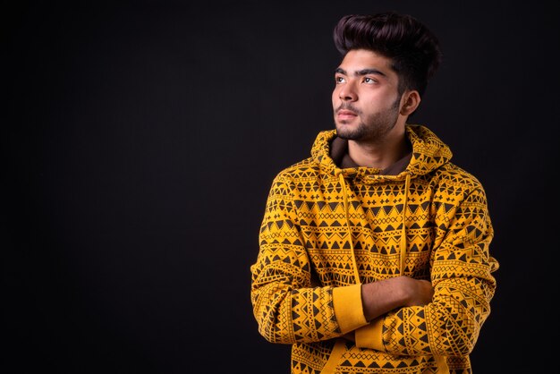 Young handsome Indian man against black background