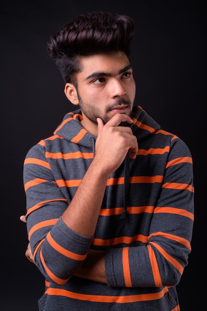 Young handsome indian man against black background