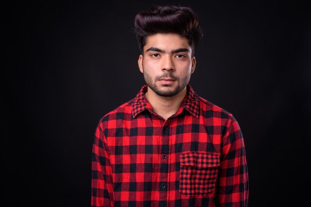 Young handsome Indian man against black background