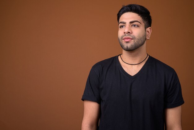 Young handsome Indian man against brown background