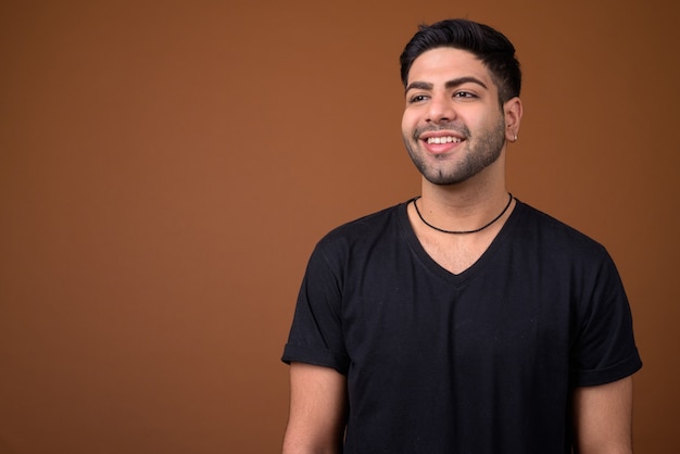 Young handsome Indian man against brown background