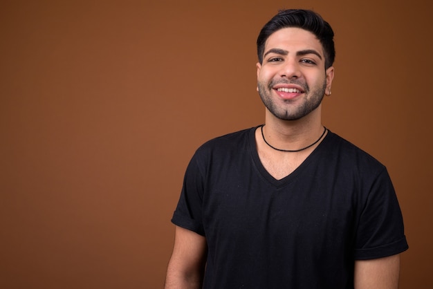 Young handsome Indian man against brown background