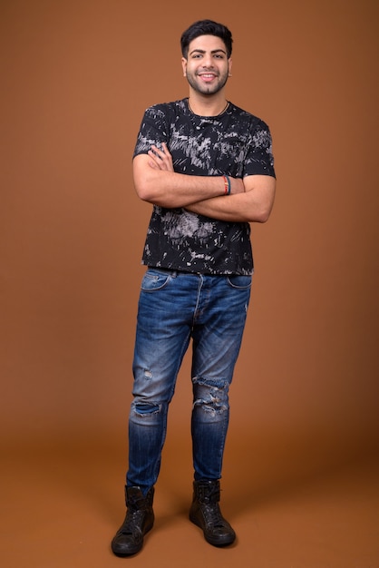 Young handsome Indian man against brown background