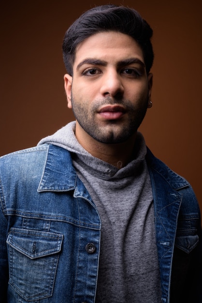 Young handsome Indian man against brown background