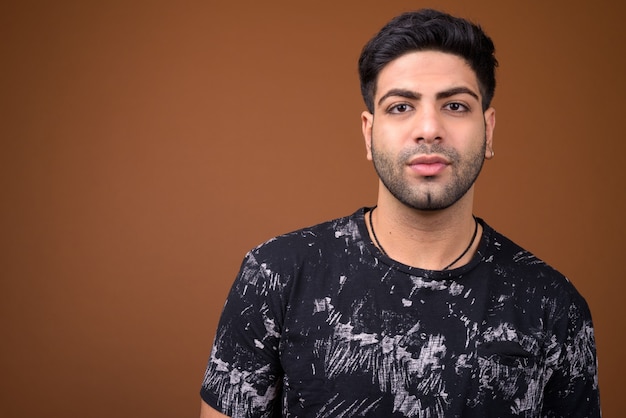 Young handsome Indian man against brown background