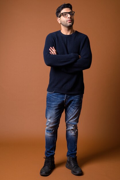 Young handsome Indian man against brown background