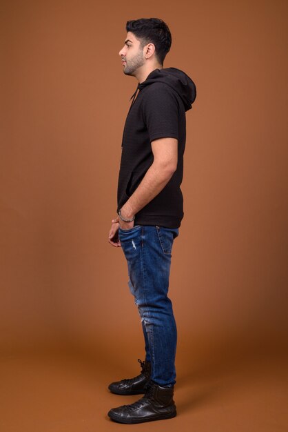 Young handsome Indian man against brown background