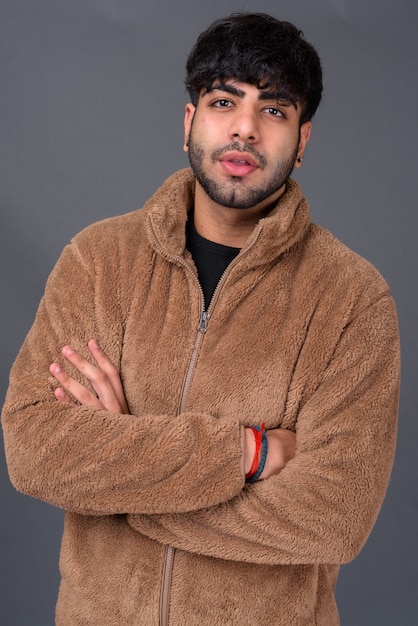 young handsome Indian man against gray space