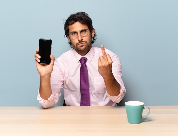 Young handsome indian man feeling angry, annoyed, rebellious and aggressive, flipping the middle finger, fighting back. business concept