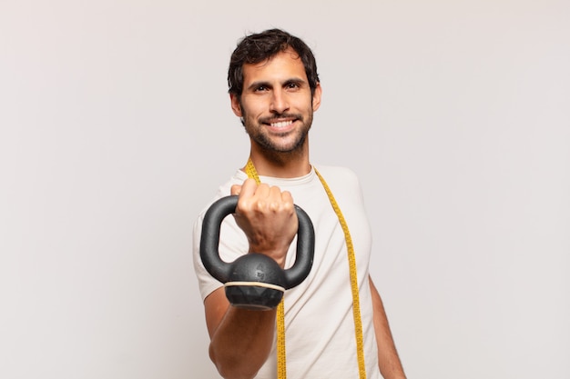 Young handsome indian man happy expression and lifting a dumbbell