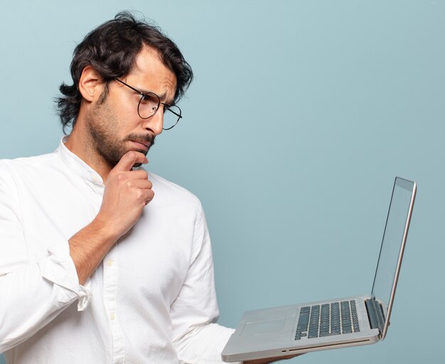 Young handsome indian man holding a laptop. business