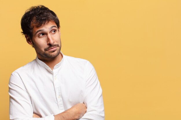 Young handsome indian man. thinking or doubting expression