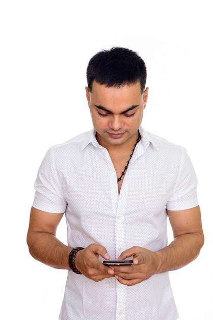 young handsome Indian man using mobile phone isolated against white space