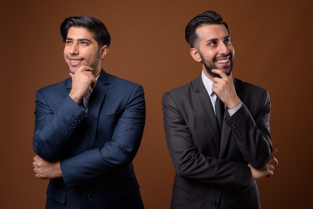 young handsome Iranian brothers together against brown wall