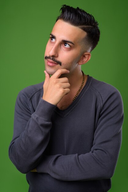 Young handsome Iranian man with mustache on green