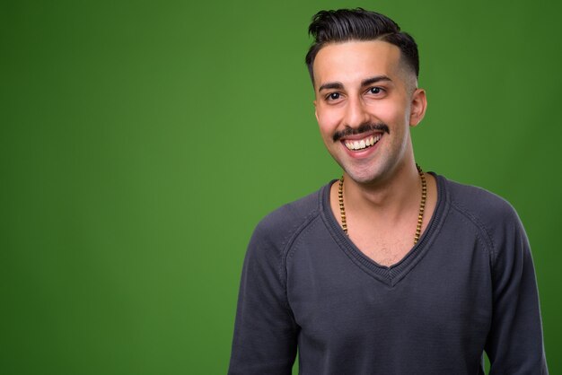 Young handsome Iranian man with mustache on green