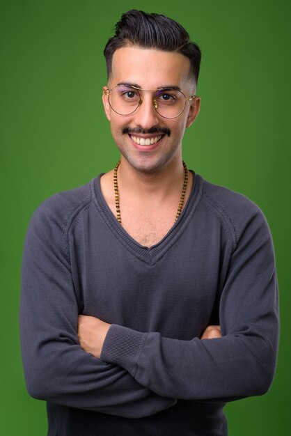 Young handsome Iranian man with mustache on green