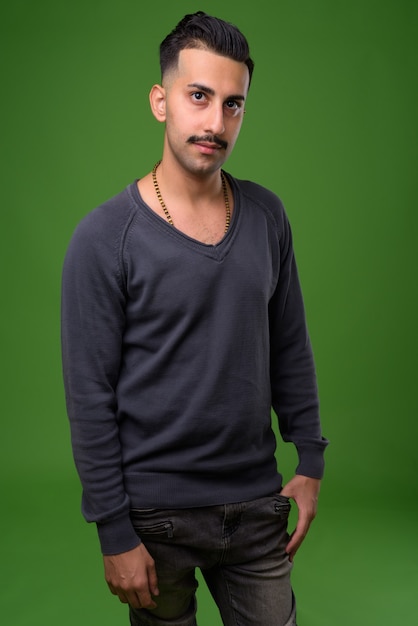 Young handsome Iranian man with mustache on green