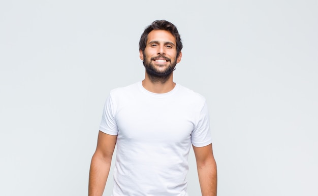 Young handsome latin man posing and looking to camera against white wall