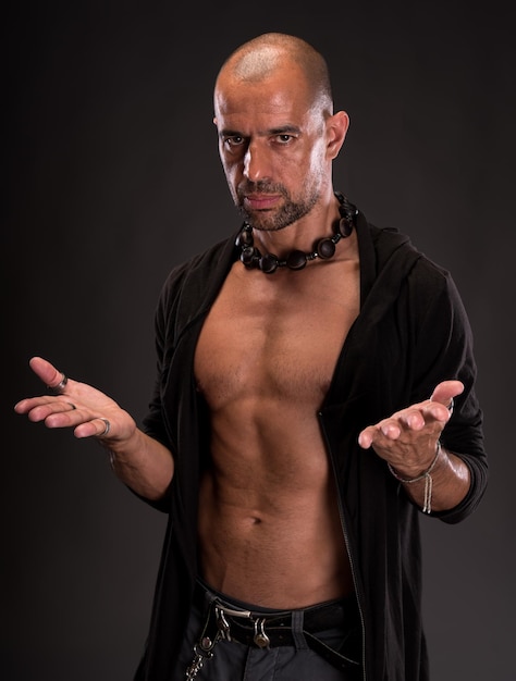 Young handsome macho man with open jacket posing on a dark background