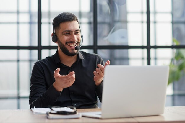 Young handsome male customer support phone operator with headset working in his office