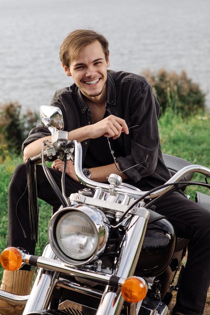 Young handsome male is sitting on his motor bike outdoors