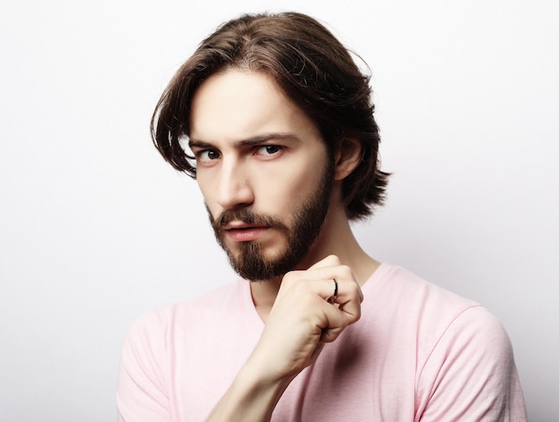Young handsome male with beard mustache and trendy hairdo wears casual pink tshirt