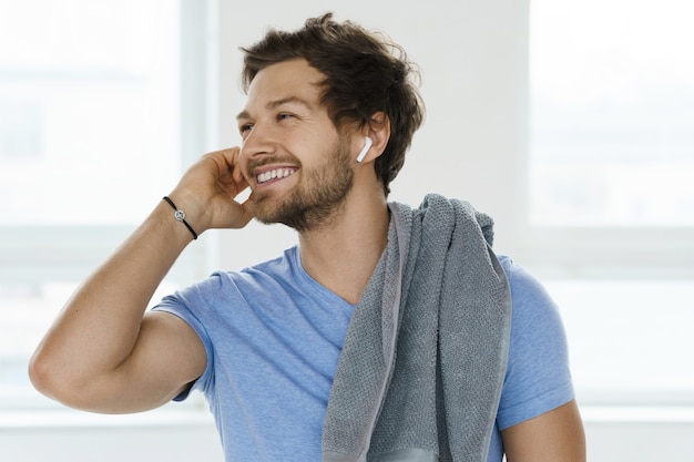 Uomo giovane e bello dopo l'allenamento fitness nella palestra luminosa