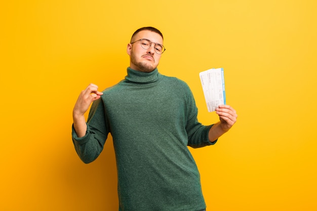 Young handsome man  against flat wall with boarding pass tickets