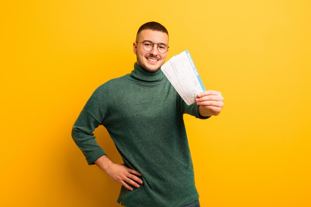 搭乗券で平らな壁に若いハンサムな男