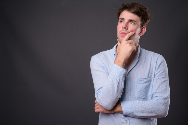 young handsome man against gray wall