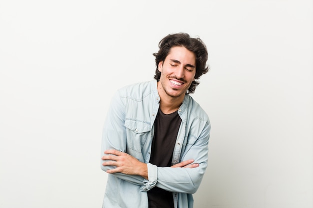 Young handsome man against a white wall laughing and having fun.