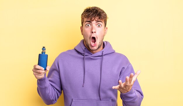 Young handsome man amazed, shocked and astonished with an unbelievable surprise. vaporizer concept