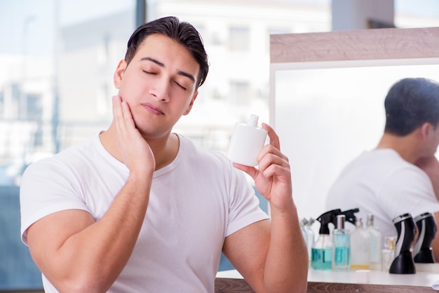 Young handsome man applying face cream