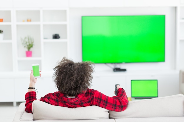 young handsome man in bathrobe enjoying free time watching television in his luxury home