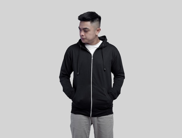 Young handsome man in black hoodie zipper posing in plain wall