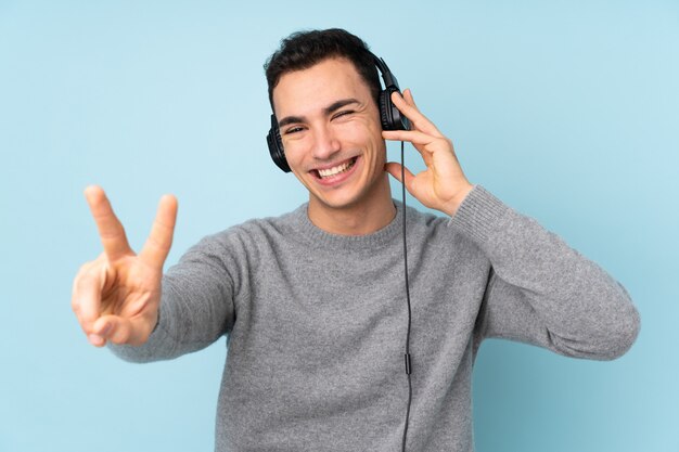 Young handsome man on blue listening music and singing